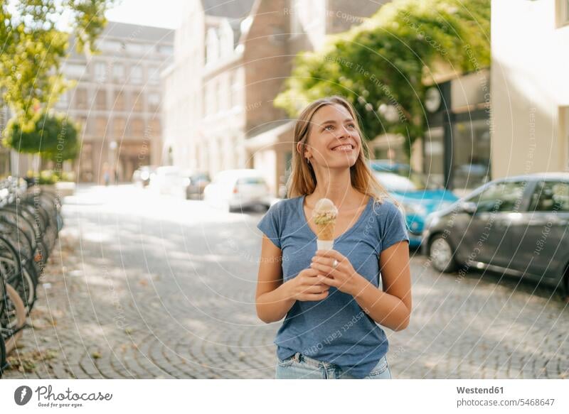 Netherlands, Maastricht, smiling blond young woman holding ice cream cone in the city Ice Cream Cone ice-cream cone Ice Cream Cones ice-cream wafer smile
