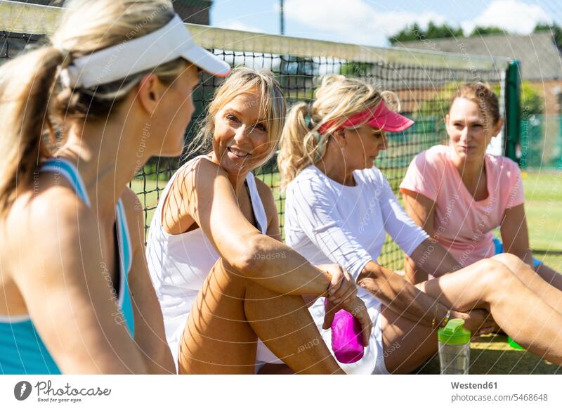 Mature women at tennis club sitting on court taking a break from playing human human being human beings humans person persons caucasian appearance