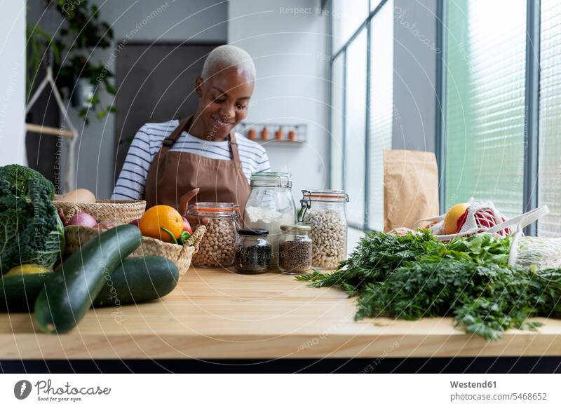 Woman with apron in kitchen , unpacking freshly bought organic fruit and vegetables human human being human beings humans person persons African black