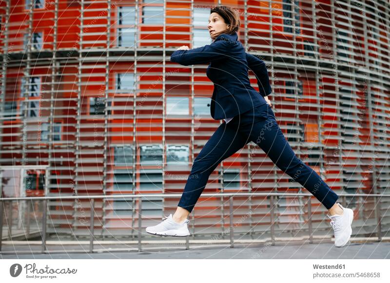 Businesswoman jumping midair outside office building in the city Leaping businesswoman businesswomen business woman business women office buildings town cities