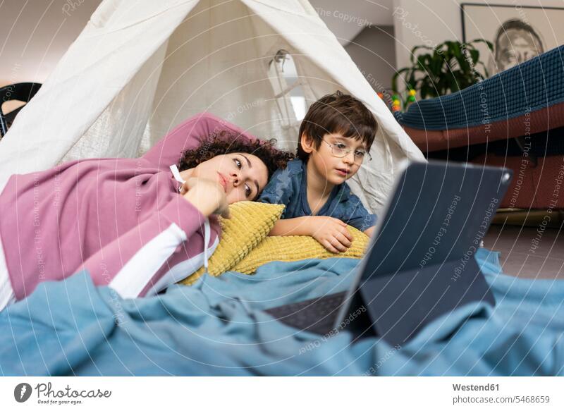 Mother and son lying in play tent, watching movie on tablet together looking looking at watching TV Looking At Tv watching television tents digitizer