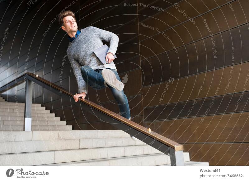 Young man jumping over railing at steps in underground walkway color image colour image indoors indoor shot indoor shots interior interior view Interiors day