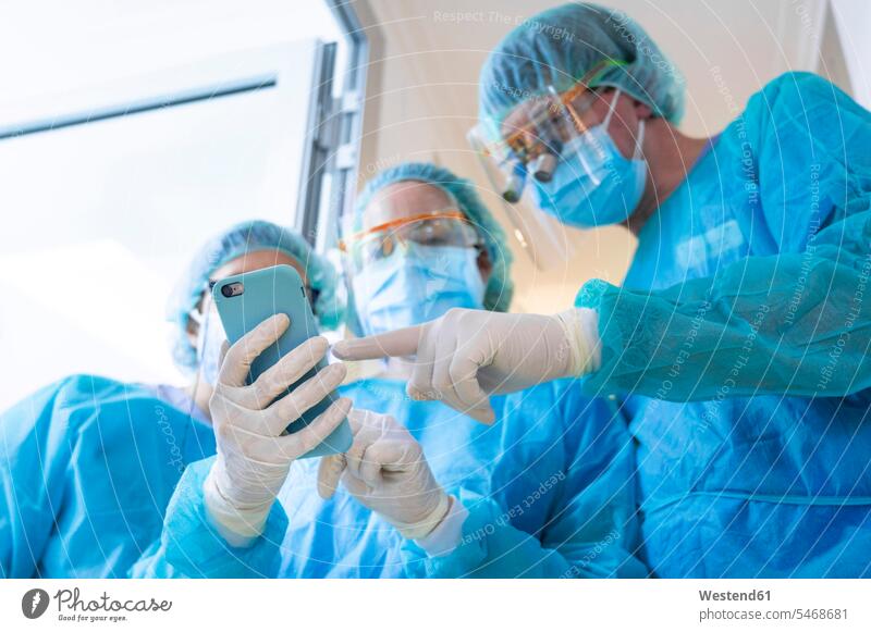 Healthcare workers discussing over mobile phone at clinic color image colour image Spain Corona Virus Coronavirus disease Covid-19 COVID19 COVID 19 pandemic