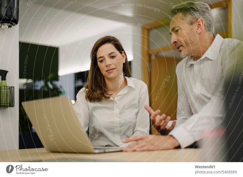 Businessman using laptop while having discussion in office color image colour image indoors indoor shot indoor shots interior interior view Interiors day
