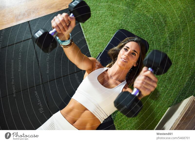 Woman training with dumbbells in a gym exercising exercise practising weight training weighttraining athlete sportswoman athletes female athlete sportswomen