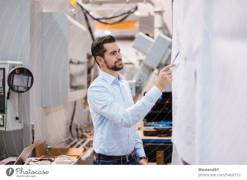Businessman in factory looking at plan plans holding Business man Businessmen Business men eyeing factories business people businesspeople business world