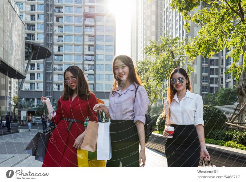 Female friends with shopping bags standing against buildings in city color image colour image Vietnam Asia leisure activity leisure activities free time