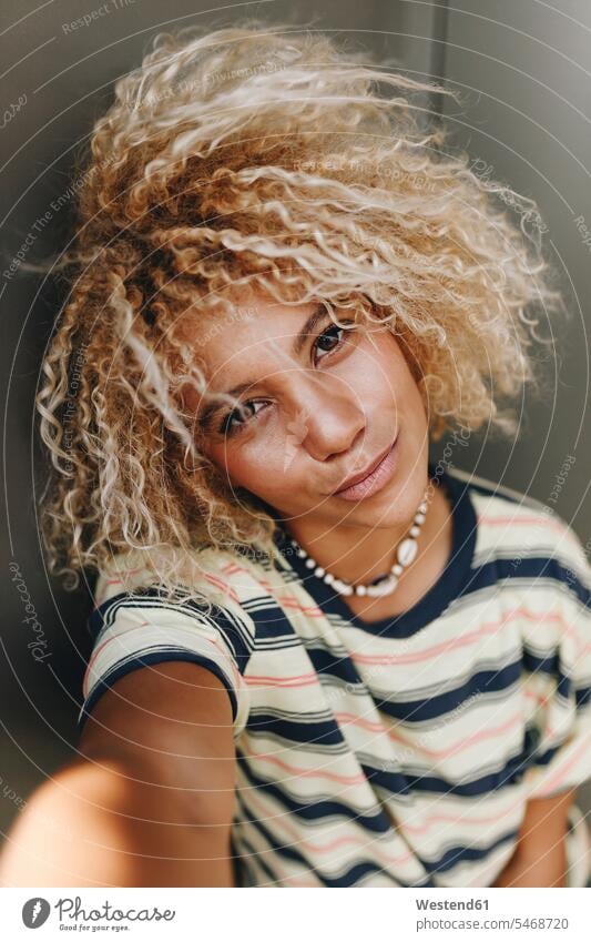 Woman with blond curly hair taking selfie against metallic wall color image colour image Spain leisure activity leisure activities free time leisure time