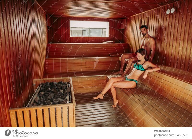 Couple relaxing in a sauna (value=0) windows swim wear bikinis Seated sit relaxation enjoy enjoyment indulgence indulging savoring heat Hot Temperature