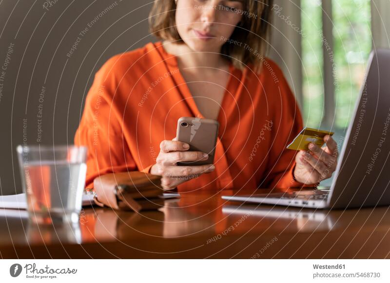 Businesswoman with credit card using smart phone at home color image colour image indoors indoor shot indoor shots interior interior view Interiors day