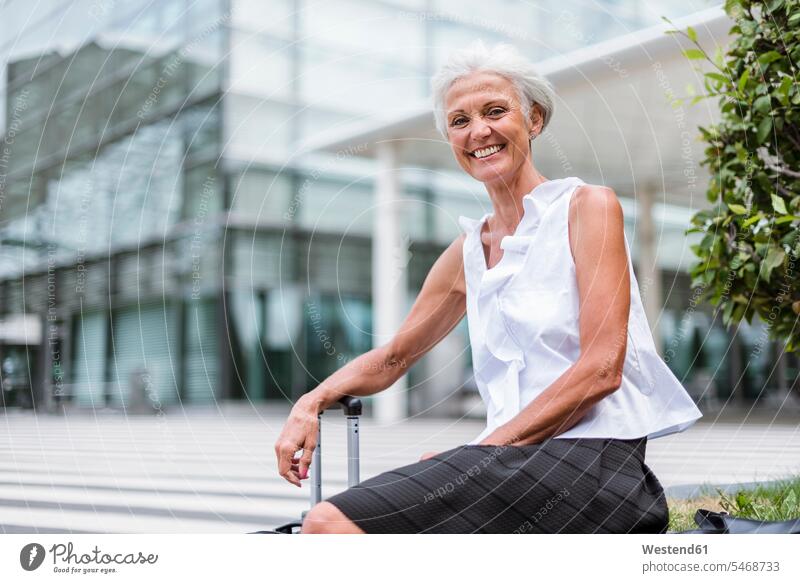 Portrait of happy senior woman with baggage sitting in the city happiness females women senior women elder women elder woman old Seated luggage town cities