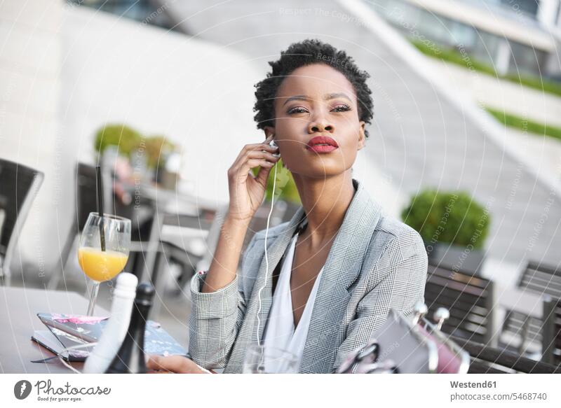 Portrait of businesswoman using earphones outdoors portrait portraits sidewalk cafe sidewalk cafes pavement cafes use businesswomen business woman