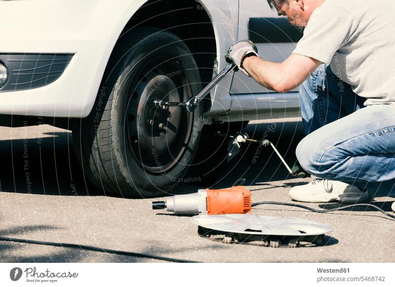 Man changing car tire car tires car tyre car tyres change man men males tire change wheel change tyre change Adults grown-ups grownups adult people persons