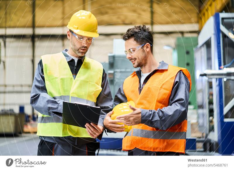 Two men wearing protective workwear holding clipboard and talking in factory speaking Protective Workwear Protective Work Wear clipboards clip-board clip-boards