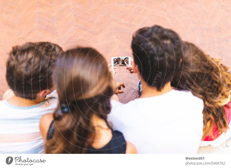 Friends taking a selfie with a cell phone group of people Group groups of people mobile phone mobiles mobile phones Cellphone cell phones friends mate persons