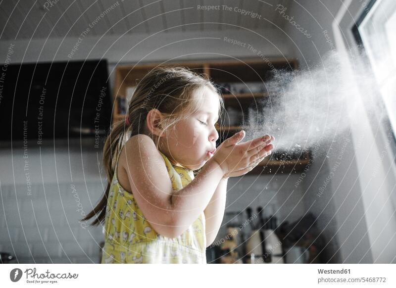 Little girl blowing flour in the air in the kitchen playing childhood mid-air midair mid air stuffed pastry dumpling females girls one person 1 one person only