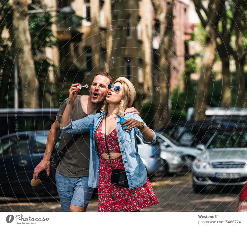 Couple blowing soap bubbles in the city together town cities towns couple twosomes partnership couples outdoors outdoor shots location shot location shots
