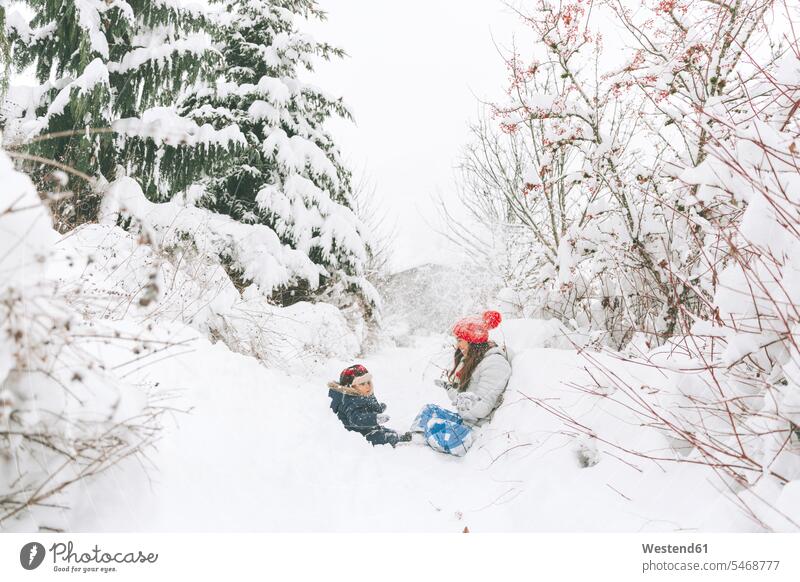Woman playing with baby in winter landscape, Canada human human being human beings humans person persons families mama mom mommy mothers mummy gloves Seated sit