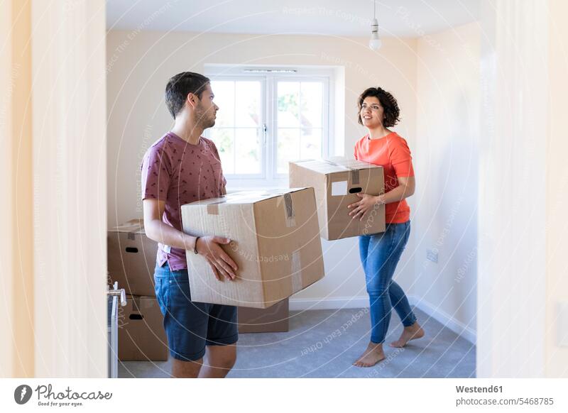 Couple moving into new home carrying cardboard boxes human human being human beings humans person persons caucasian appearance caucasian ethnicity european 2