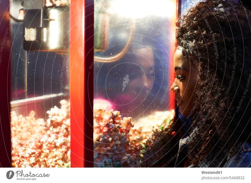 Young woman looking at popcorn in glass case at fair human human being human beings humans person persons African black black ethnicity coloured 1