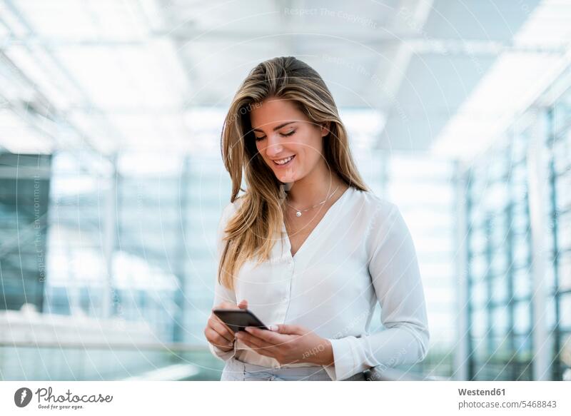 Smiling young woman standing at railing using cell phone mobile phone mobiles mobile phones Cellphone cell phones businesswoman businesswomen business woman