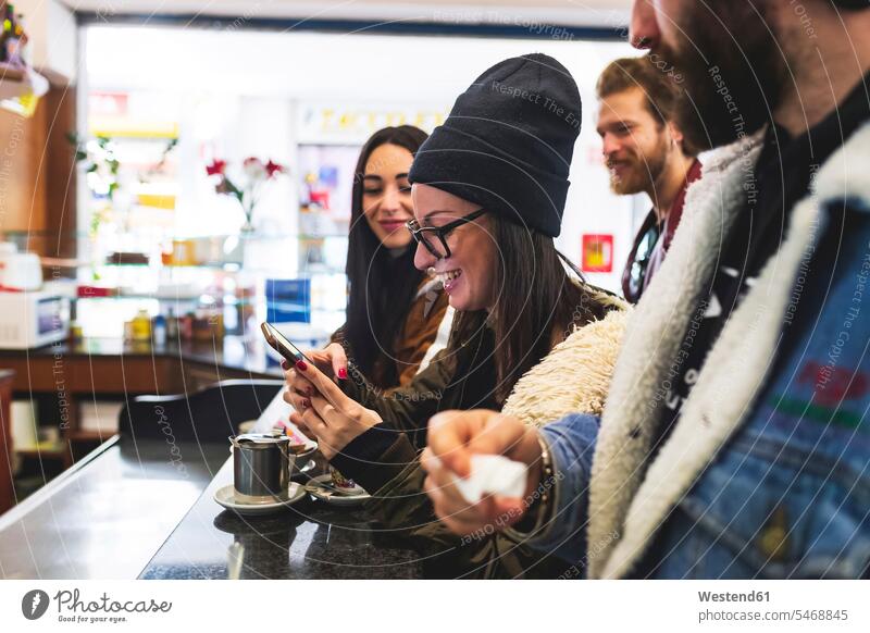 Smiling woman using smart phone while enjoying with friends in cafe color image colour image leisure activity leisure activities free time leisure time