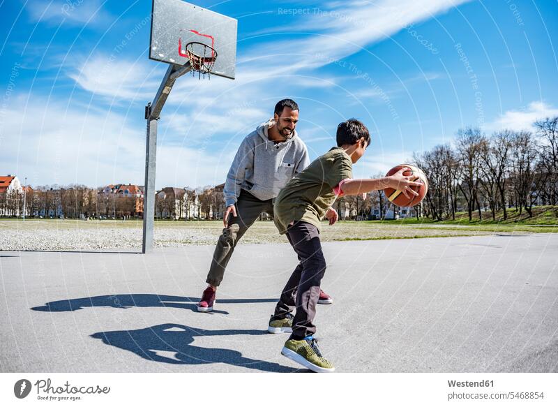 Father and son playing basketball on court outdoors sons manchild manchildren father pa fathers daddy dads papa basketballs basketball ground basketball court