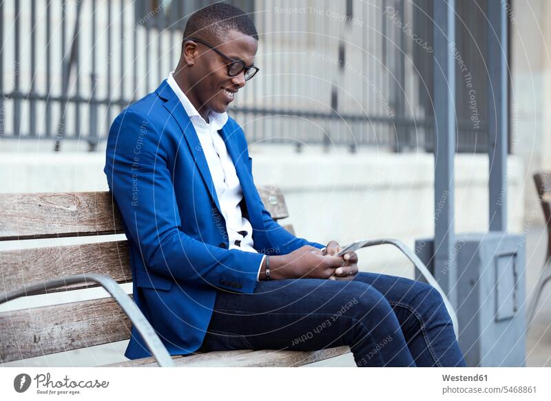 Young businessman wearing blue suit jacket sitting on bench and using smartphone Occupation Work job jobs profession professional occupation business life