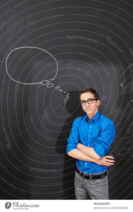 Portrait of confident young man standing at blackboard with thought bubble Thought Bubble blackboards men males portrait portraits smiling smile Adults