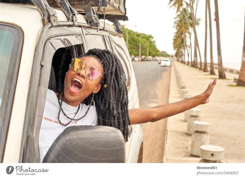 Portrait of screaming woman with dreadlocks leaning out of car window, Maputo, Mozambique T- Shirt t-shirts tee-shirt motor vehicles road vehicle road vehicles