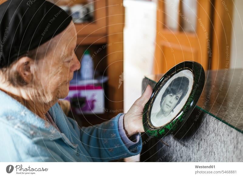 Senior woman looking at old picture frame at home color image colour image indoors indoor shot indoor shots interior interior view Interiors day daylight shot