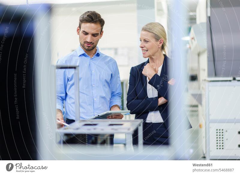 Businesswoman discussing with young male technician in illuminated factory color image colour image indoors indoor shot indoor shots interior interior view