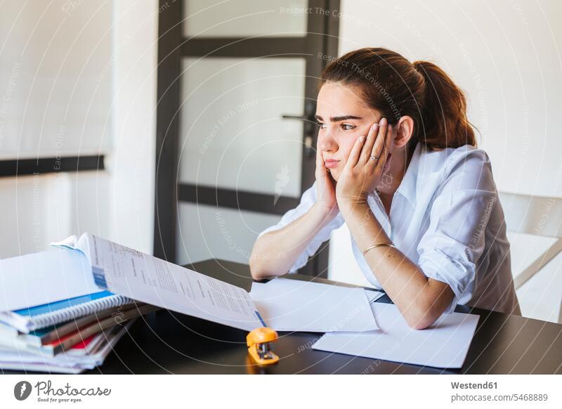 Frustrated female student with documents at desk at home Tables desks learn Seated sit study pessimistic despaired Desperation Emotions Feeling Feelings