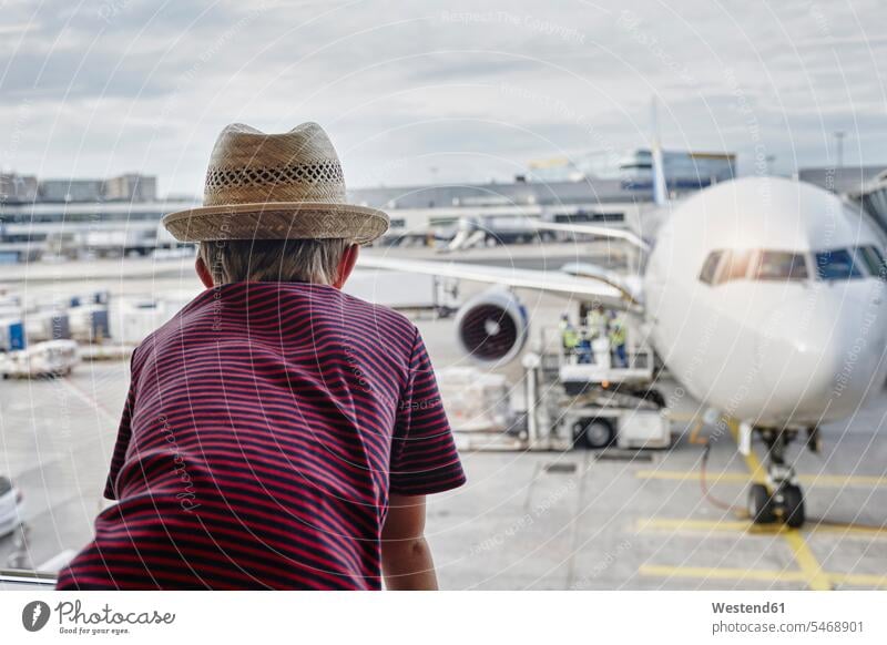 Boy wearing straw hat looking through window to airplane on the apron movement area maneuvering area aeroplanes airplanes straw hats airport airports windows