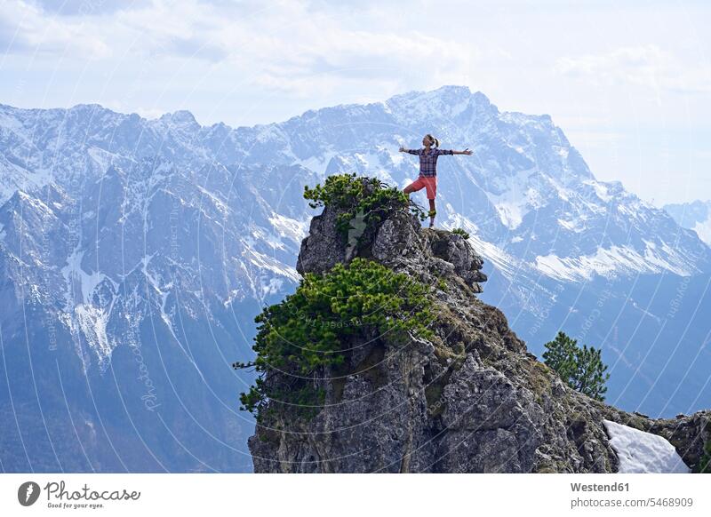 Woman standing with arms outstretched on rocky mountain peak while looking at landscape against sky color image colour image outdoors location shots