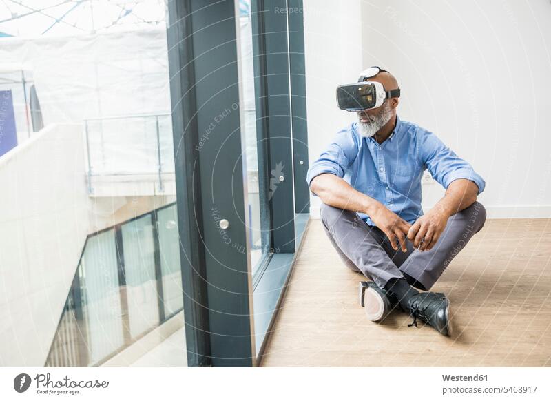 Businessman wearing VR glasses sitting on the floor at the window virtual reality floors Seated Business man Businessmen Business men windows specs Eye Glasses