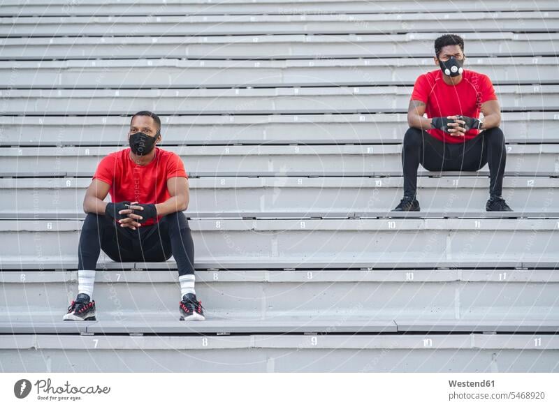 Two sportsmen wearing masks sitting on stairs friends mate gloves Seated colour colours athletes Sports Person Sportsman Sportsmen Sportspeople Sportsperson