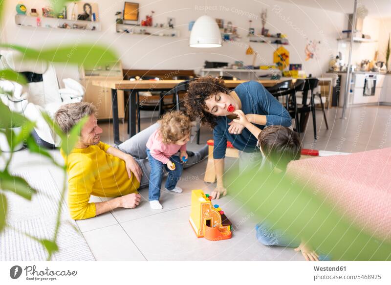 Happy family playing with their kids on a weekend families daughter daughters toy toys home at home son sons manchild manchildren mother mommy mothers mummy