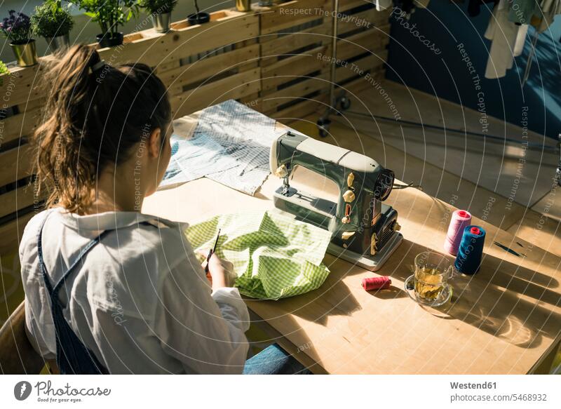 Back view of fashion designer at work in her studio studios desk worktable work table work desk fashion designers female fashion designer