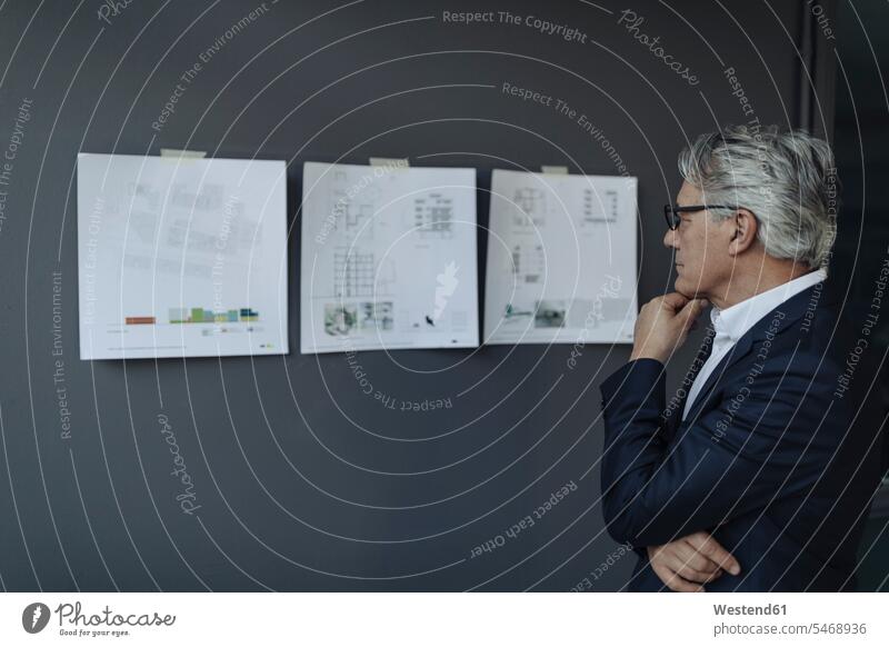Senior businessman looking at papers hanging on the wall Occupation Work job jobs profession professional occupation architects business life business world