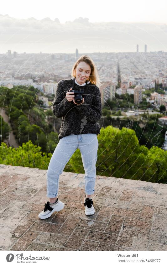 Young woman with camera above the city at sunrise, Barcelona, Spain human human being human beings humans person persons caucasian appearance