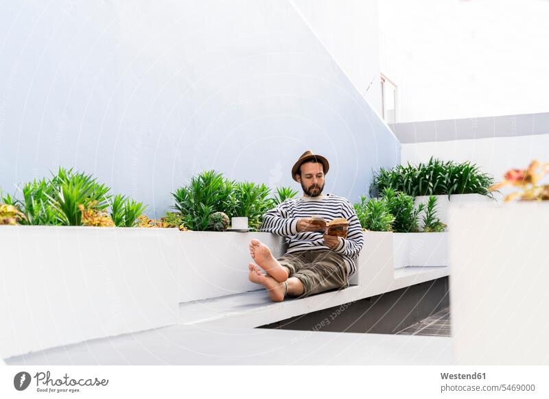 Man sitting on balcony reading a book human human being human beings humans person persons caucasian appearance caucasian ethnicity european 1 one person only