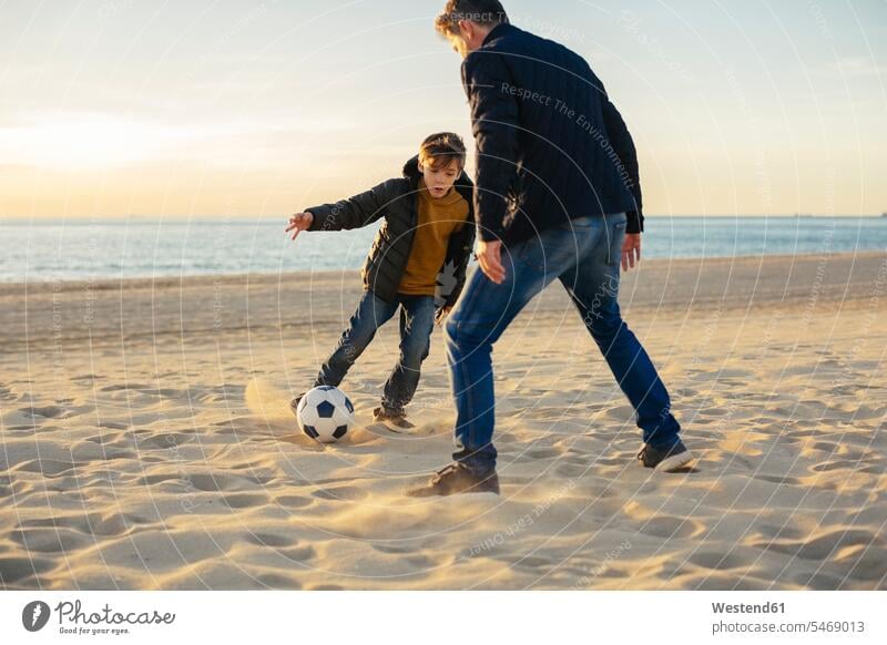 Father and son playing football on the beach soccer ball soccer balls footballs father pa fathers daddy dads papa beaches sons manchild manchildren parents