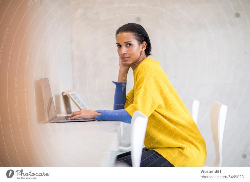 Portrait of young woman wearing yellow pullover using laptop Laptop Computers laptops notebook use females women sweater jumper Sweaters portrait portraits