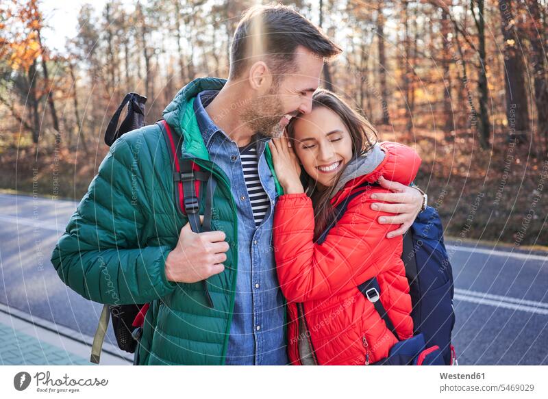 Happy couple embracing on a road in the woods during backpacking trip forest forests excursion Getaway Trip Tours Trips happiness happy embrace Embracement hug