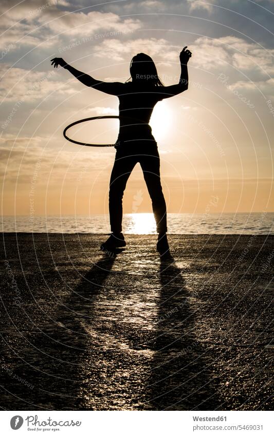 Happy woman playing with hula hoop at harbour during sunset Contemporary front view frontal outdoor outdoors outside human human being human beings humans
