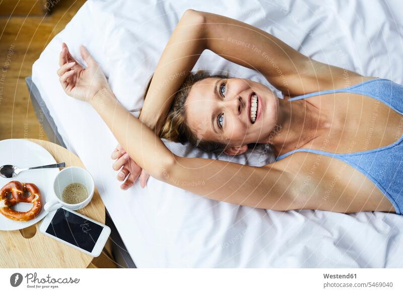 Portrait of laughing young woman lying in bed portrait portraits Laughter females women beds laying down lie lying down positive Emotion Feeling Feelings