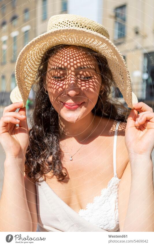 Close-up of smiling beautiful woman with eyes closed wearing hat in city on sunny day color image colour image leisure activity leisure activities free time