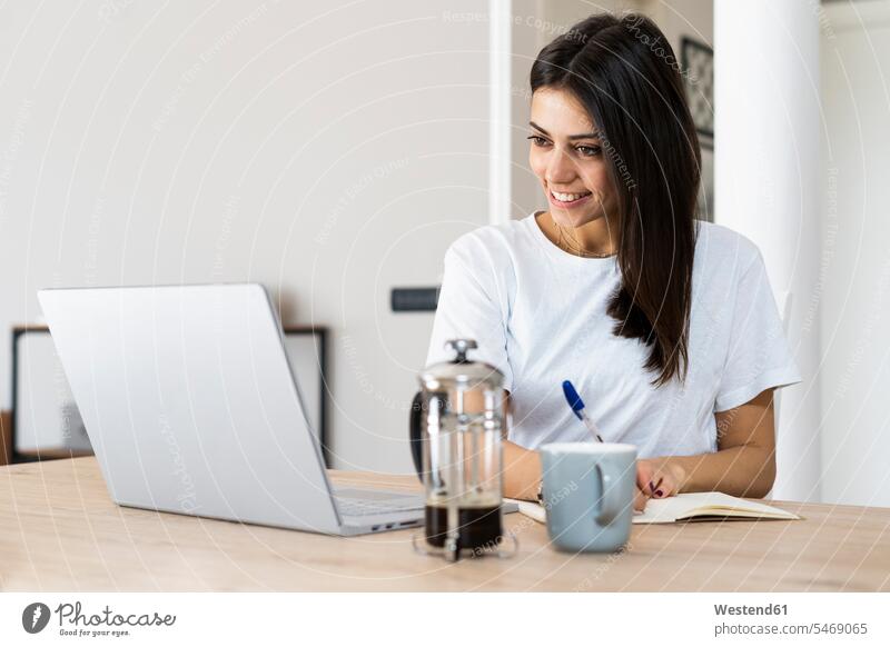 Young woman with laptop taking notes at home human human being human beings humans person persons caucasian appearance caucasian ethnicity european 1