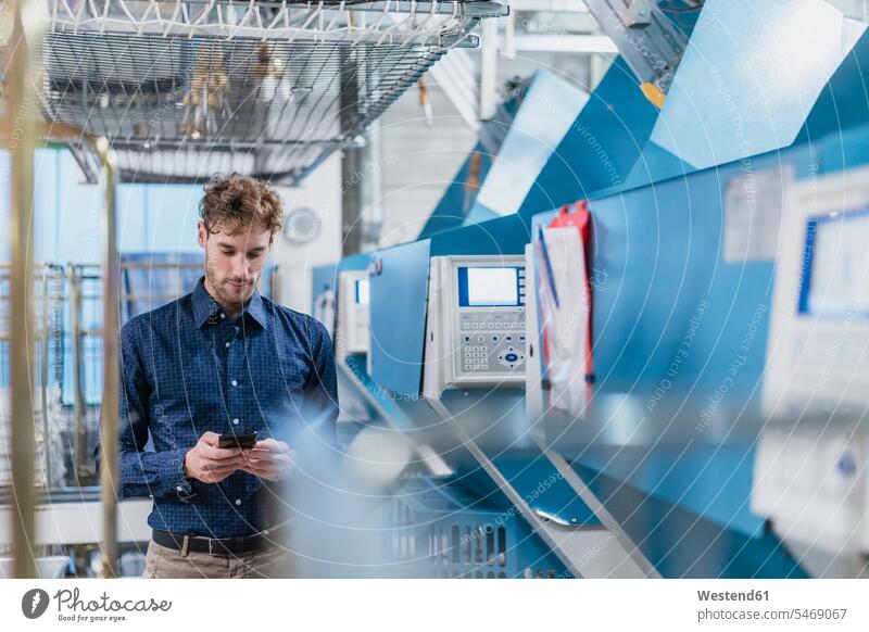 Young businessman using smartphone in a factory human human being human beings humans person persons caucasian appearance caucasian ethnicity european 1